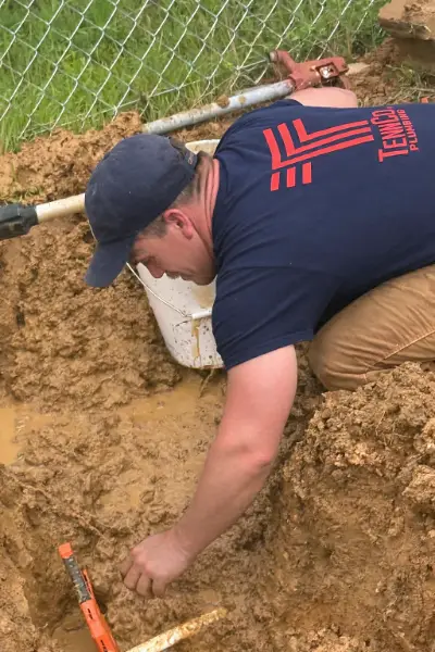 plumber making water line connection to water main in the yard